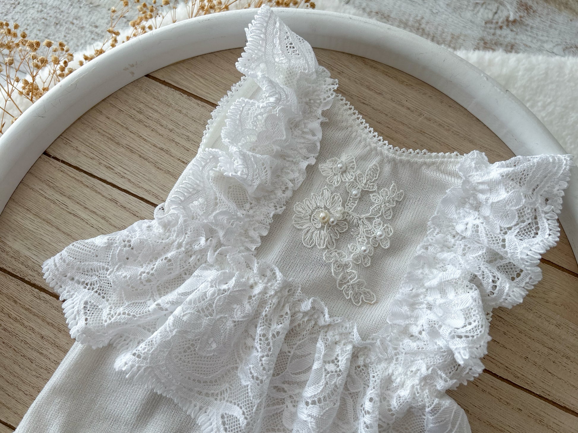 Close-up of embroidered floral lace and pearl bead detail on front panel