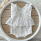 Back view of the white romper with V cut and pearl button closure on wooden surface