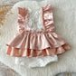 Peach satin and lace baby romper with ruffle details, displayed on soft background