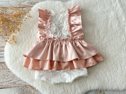 Peach satin and lace baby romper with ruffle details, displayed on soft background