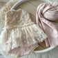 Flat lay of blush pink romper with matching wrap – styled setup