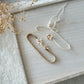 Neutral elastic baby headband with ivory flowers and blush pink pearl accents, styled flat on a wooden tray.

