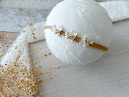 Newborn photography headbands in neutral tones with vintage-inspired floral and pearl details.