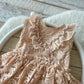 Front view of blush lace baby romper with ruffled skirt for sitter session (6–12 months)
