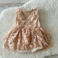 Flat lay of sitter romper dress with blush lace, ruffles, and soft lining on white background