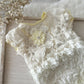 White lace garment with floral details on a wooden surface