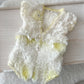 Delicate lace baby romper with floral details on a wooden surface