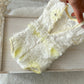 White lace garment with yellow accents held over a wooden frame.