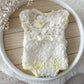 Delicate floral baby romper on a wooden surface with decorative elements.
