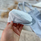 Hand holding a textured light blue newsboy cap for photography shoots.