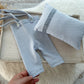 Baby outfit with shorts and bib on a wooden tray, held by a hand.