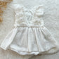 The back of a white muslin sitter photography dress that closes with pearl button