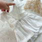 Close-up of a white textured fabric with a hand holding it, on a light background.