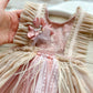 Close-up of a baby dress with floral details held by a hand.