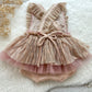Back view of baby girl romper featuring crisscross ruffled straps and soft polka dot mesh skirt in blush tones.