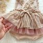 Pink polka dot dress with a hand holding it against a textured white background