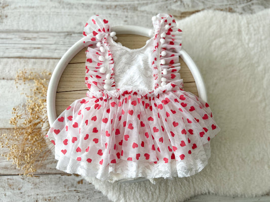 Baby girl heart romper dress with red hearts, ruffle straps, and lace details – perfect for Valentine’s Day