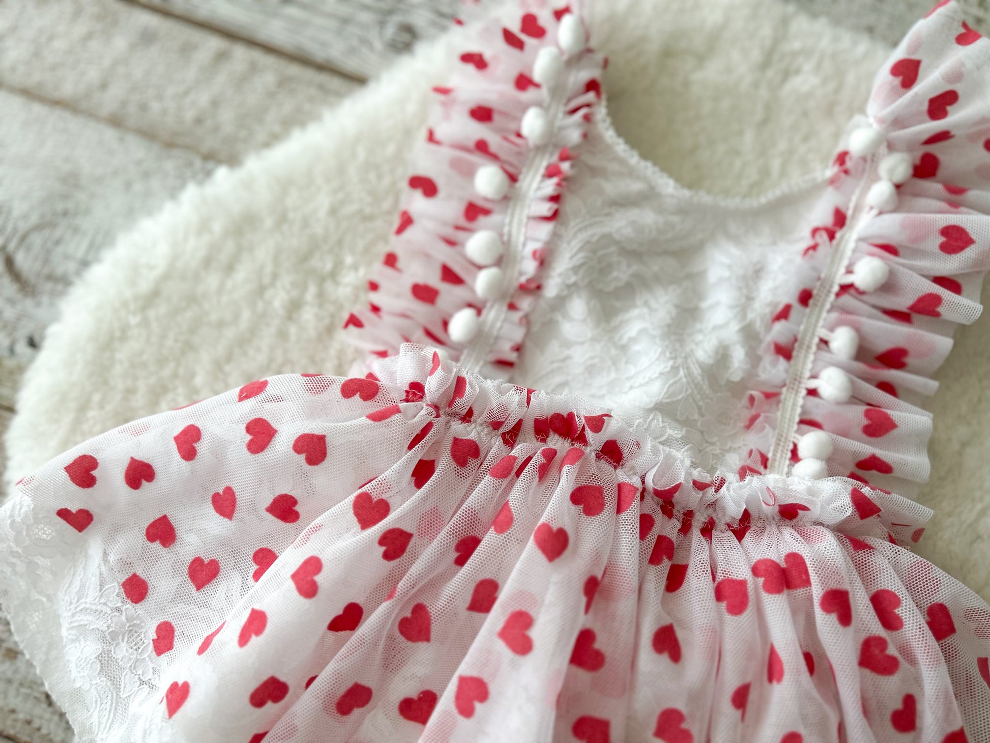 Close up on the white sitter dress with pompoms and red hearts