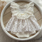 White lace newborn romper and matching posing pillow set on neutral background

