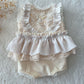 Flat lay of cream lace newborn outfit on wood backdrop