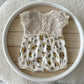 Newborn photo romper with ivory lace top and yellow floral bottom – flat lay view