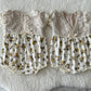 Ivory lace baby romper styled on soft flokati rug – vintage floral prop setup