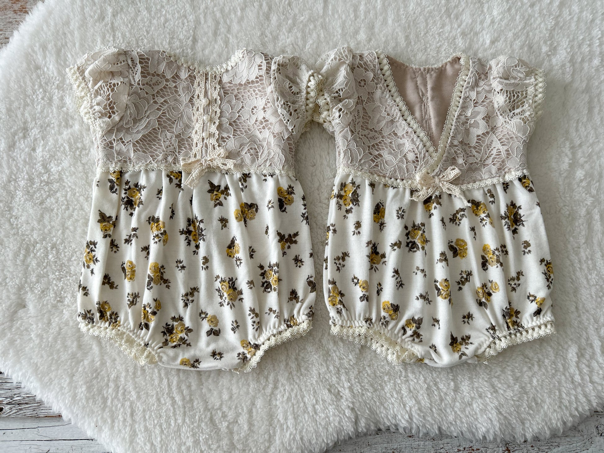 Ivory lace baby romper styled on soft flokati rug – vintage floral prop setup
