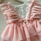 Displays the romper’s back design with white velvet bottom and the continuation of the ruffled sleeves and skirt.
