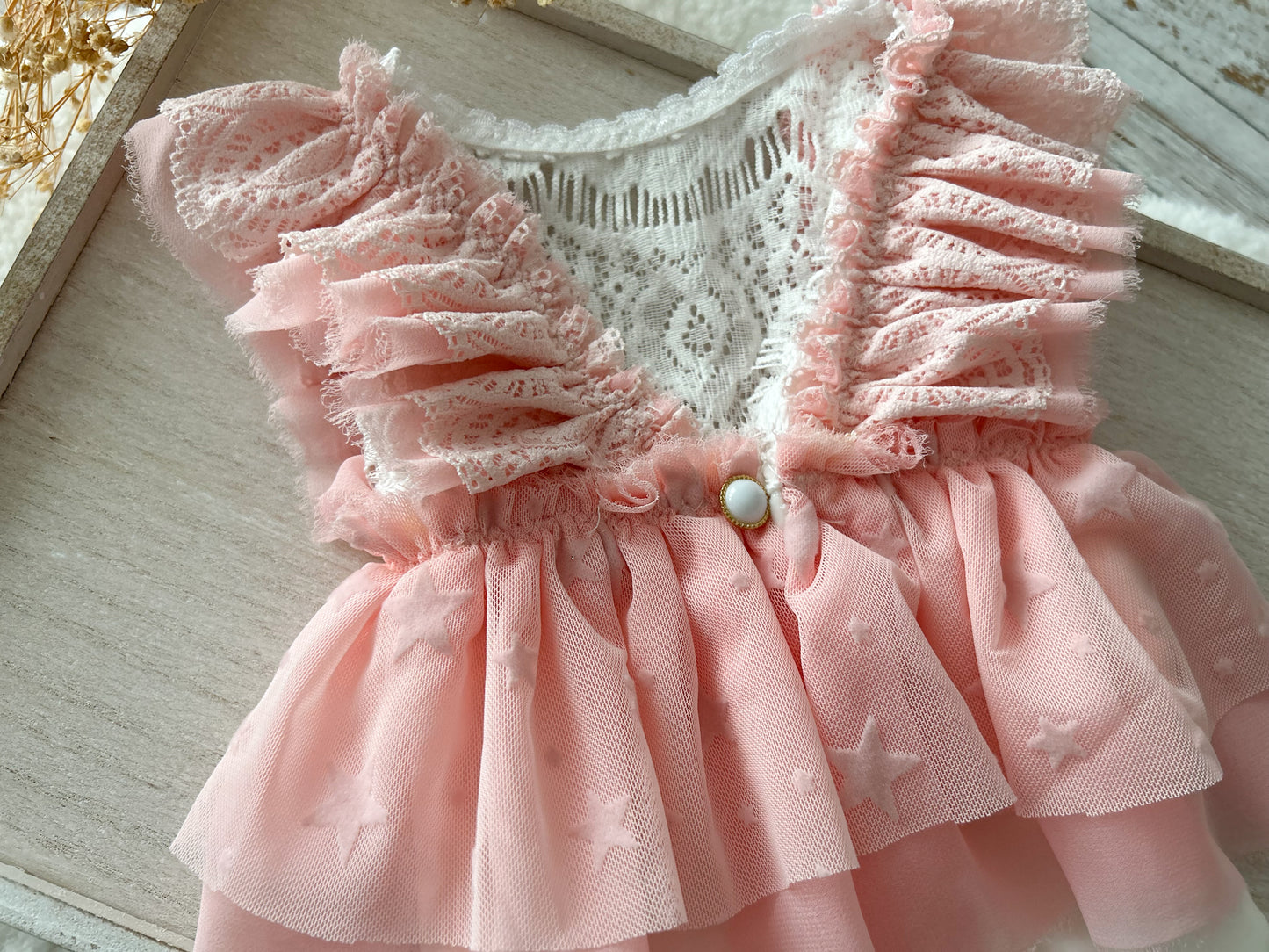 Displays the romper’s back design with white velvet bottom and the continuation of the ruffled sleeves and skirt.
