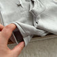 Gray baby onesie being held by a hand on a light background