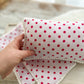 newborn posing pillow with white pompom trim, in light pink with polka dots