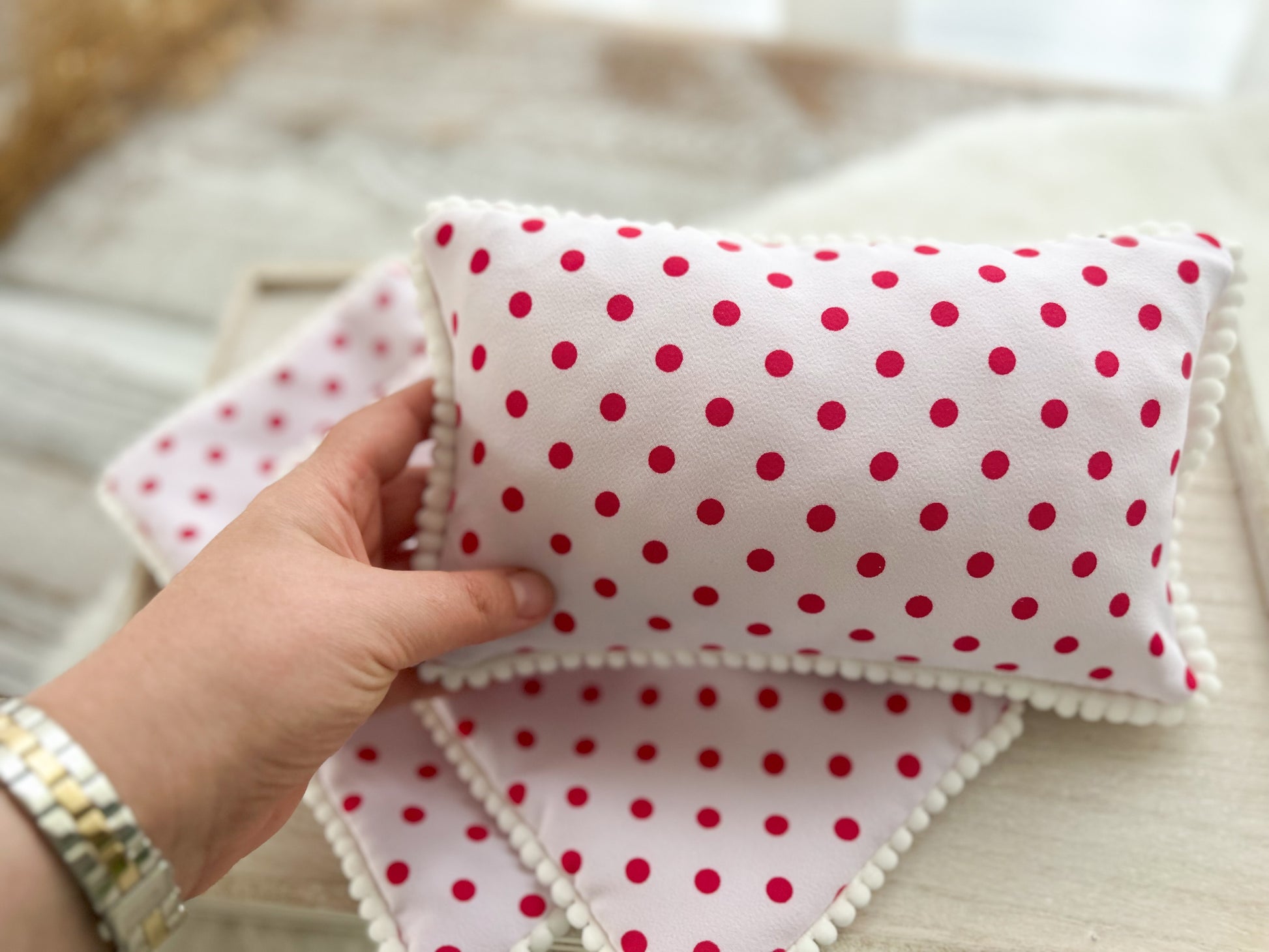 newborn posing pillow with white pompom trim, in light pink with polka dots