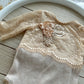 Beige lace baby outfit on a wooden surface