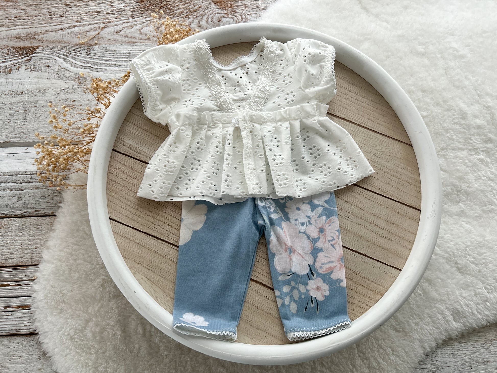 White blouse with floral pants on a white plate on a wooden surface