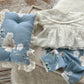 Newborn photography outfit with white top and floral pants set on wooden background