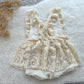 Back view of baby girl romper with criss-cross ruffled straps and a tied bow