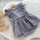 Baby romper for sitter photography with ruffled details on a wooden surface