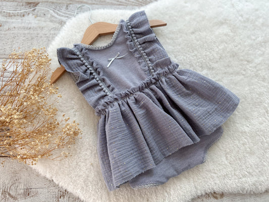 Baby romper for sitter photography with ruffled details on a wooden surface