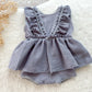 Gray baby romper with ruffled details on a white surface