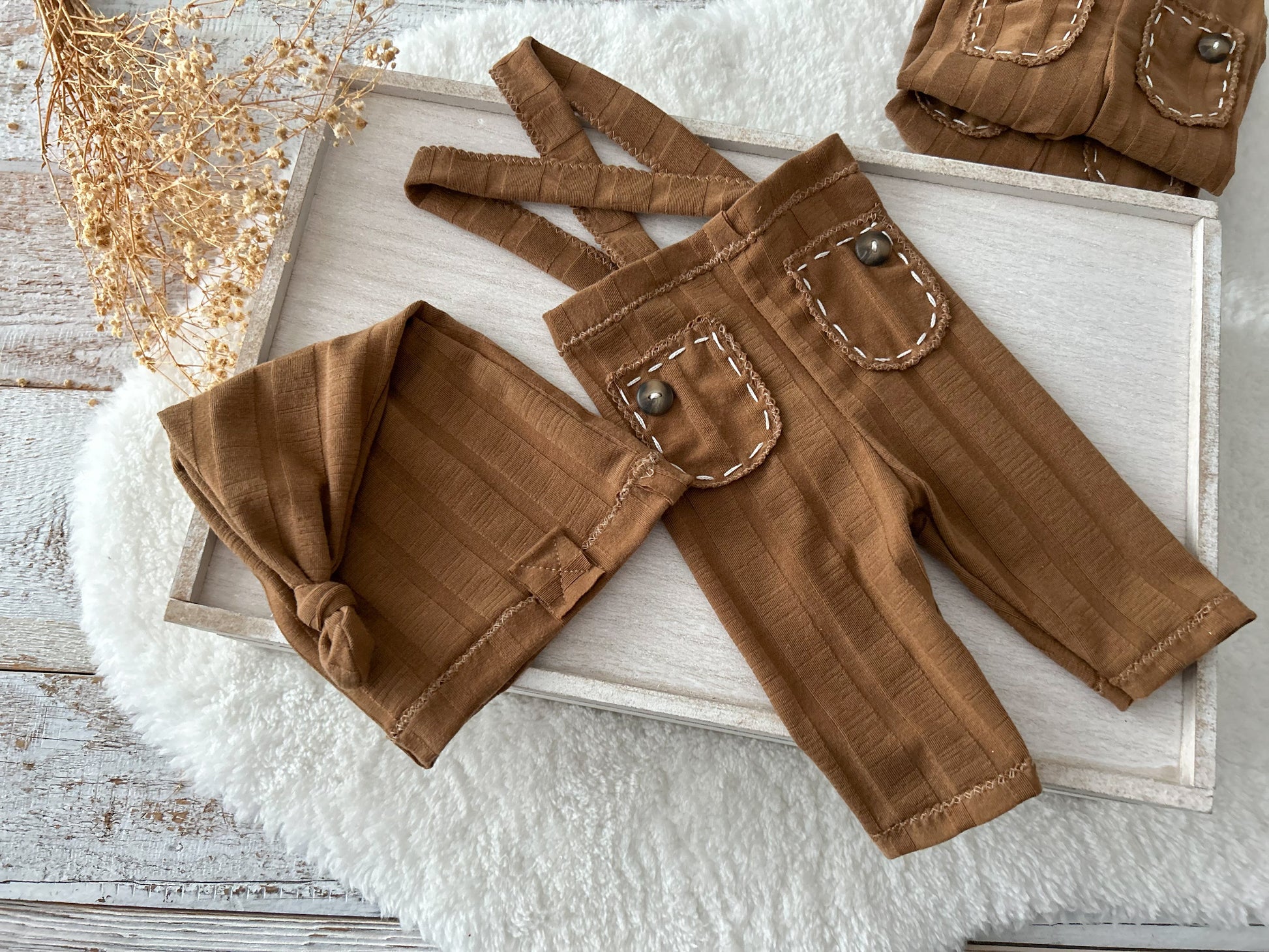 Newborn photo prop set in chestnut brown, including stretchy pants with sewn-in suspenders and cozy sleepy hat.