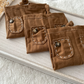 Detailed view of the brown ribbed fabric texture and hand-stitched accents on the newborn suspender pants.