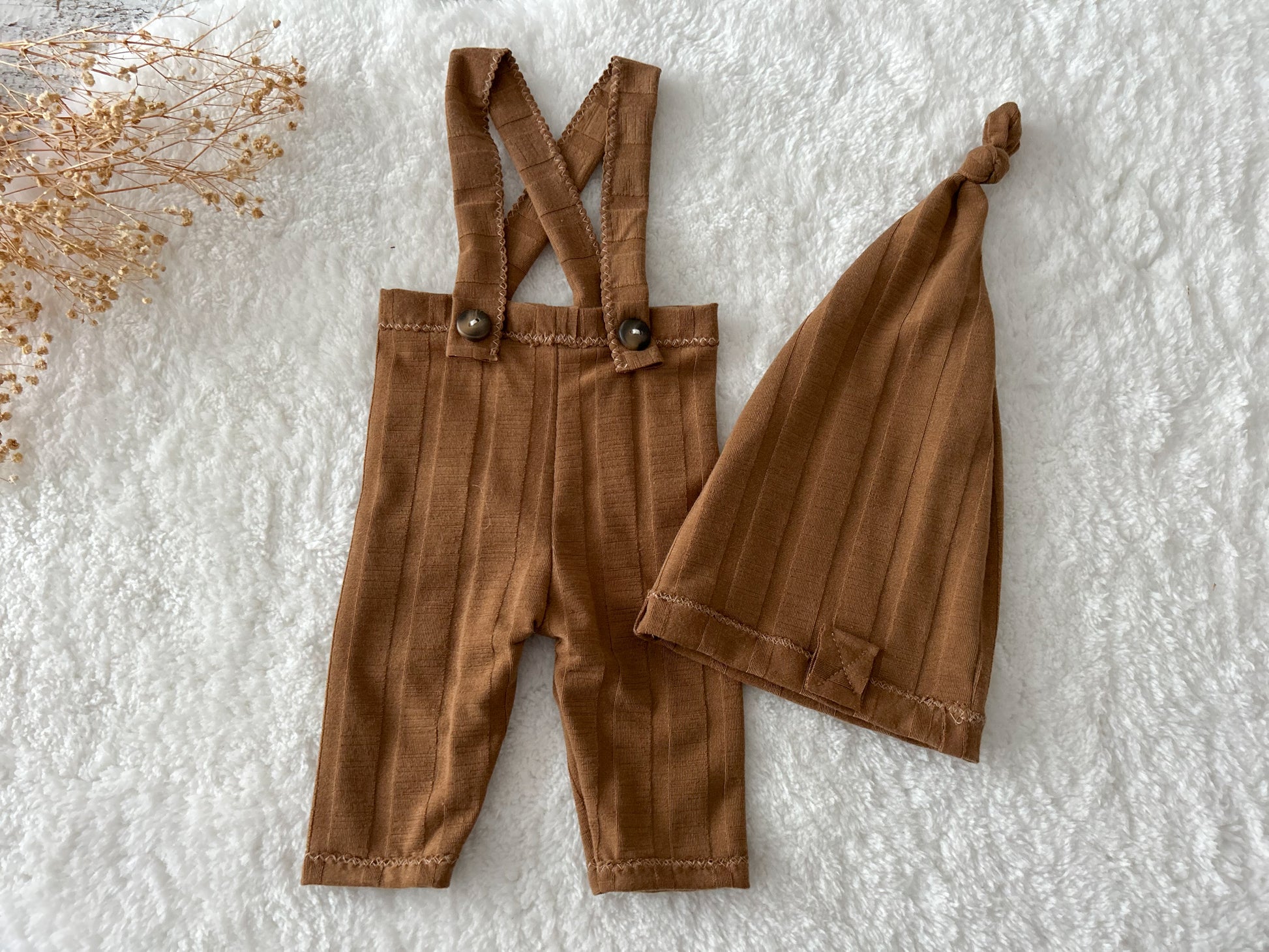 Newborn photo prop set in chestnut brown, including stretchy pants with sewn-in suspenders and cozy sleepy hat.