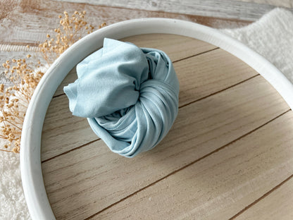 Soft blue stretchy newborn wrap rolled up as a photo prop.