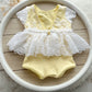 The back of newborn romper in pale yellow color with white floral lace for the skirt and top part. 