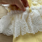Close-up on the back of the romper with ruffled skirt attached at the waistline and a pearl button closure. 