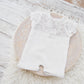 This newborn girl romper features short sleeves and legs and a back opening that ties with lace strings in a bow. Perfect as newborn photo prop or baby shower gift
