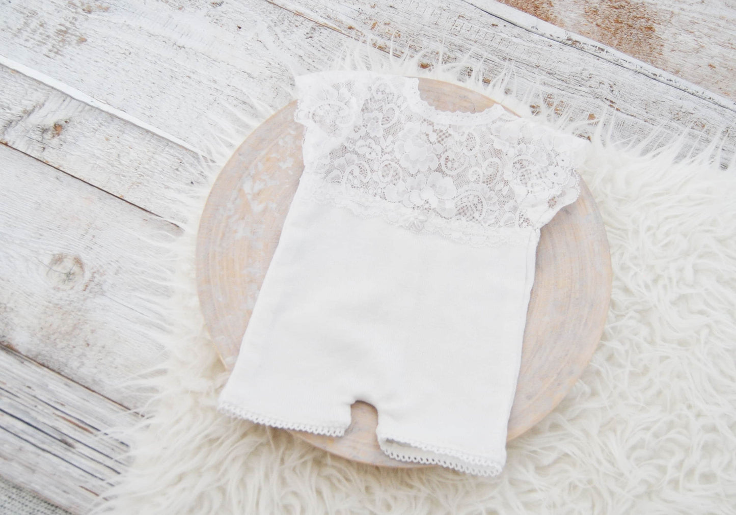 This newborn girl romper features short sleeves and legs and a back opening that ties with lace strings in a bow. Perfect as newborn photo prop or baby shower gift