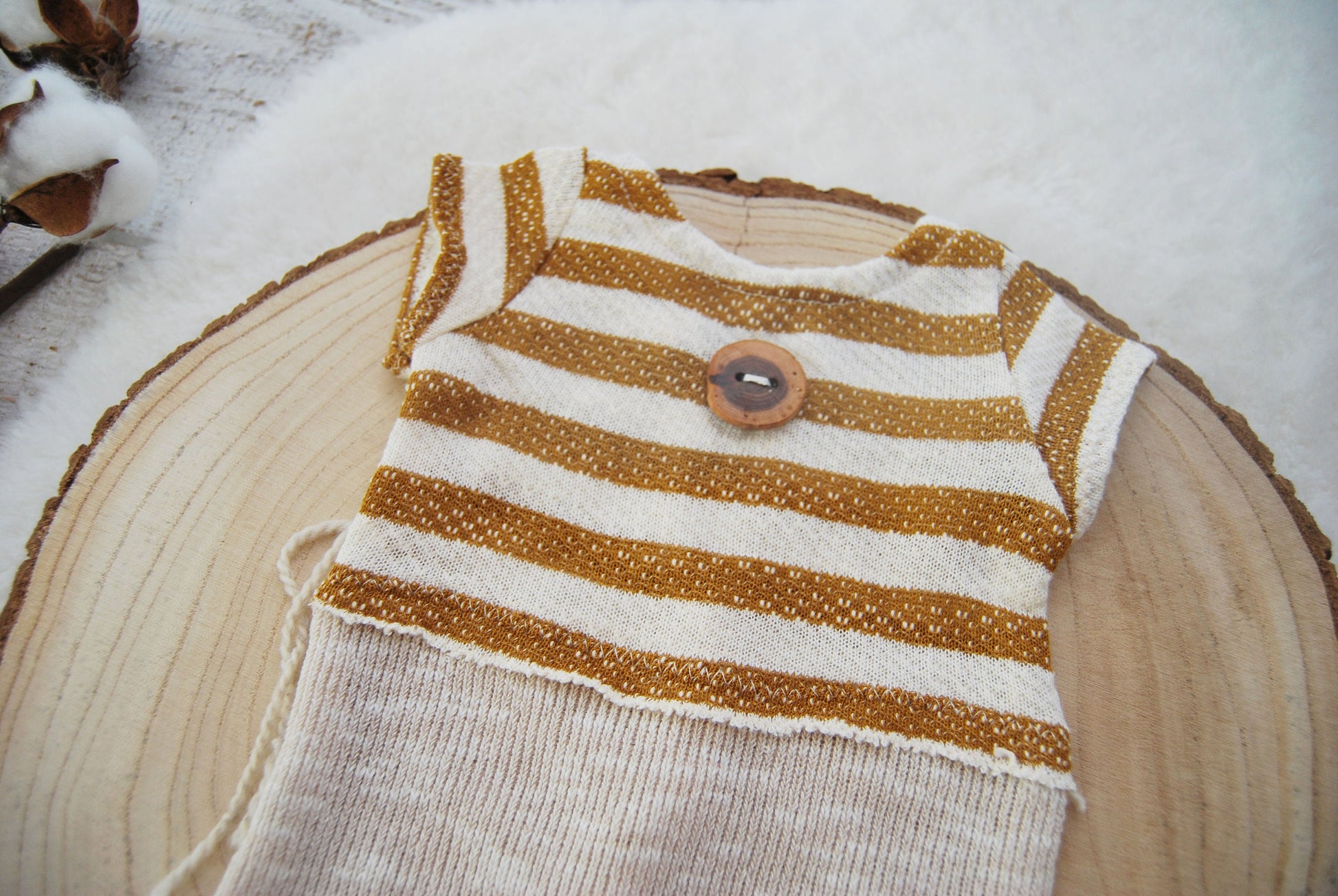 This newborn romper is decorated on top with a big handmade wooden button that looks very cute on the striped fabric. This baby boy overall features short sleeves and has a matching sleepy knot hat.