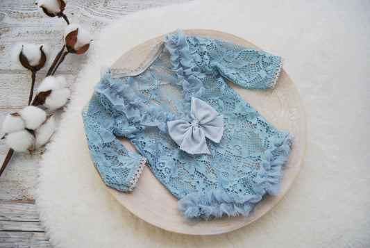 Lace newborn girl outfit for photo shoots in a powder blue color. It features opened back decorated with ruffles and a bow.