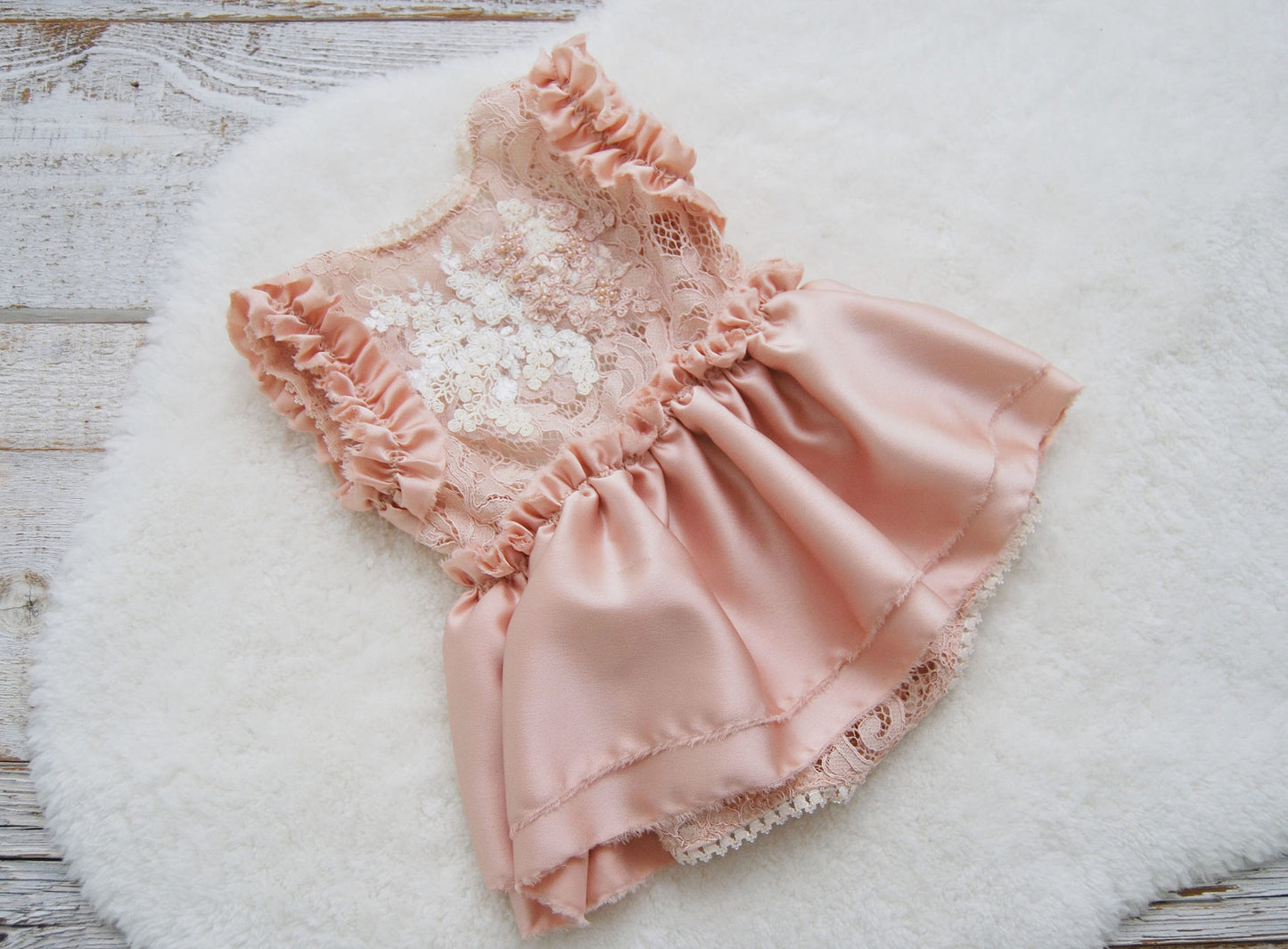 The front part of this sitter photography outfit in dusty pink color. Made of lace with beautiful texture and additional la appliques decoration on front in a lighter pink and white color. The bottom is a satin ruffled skirt.